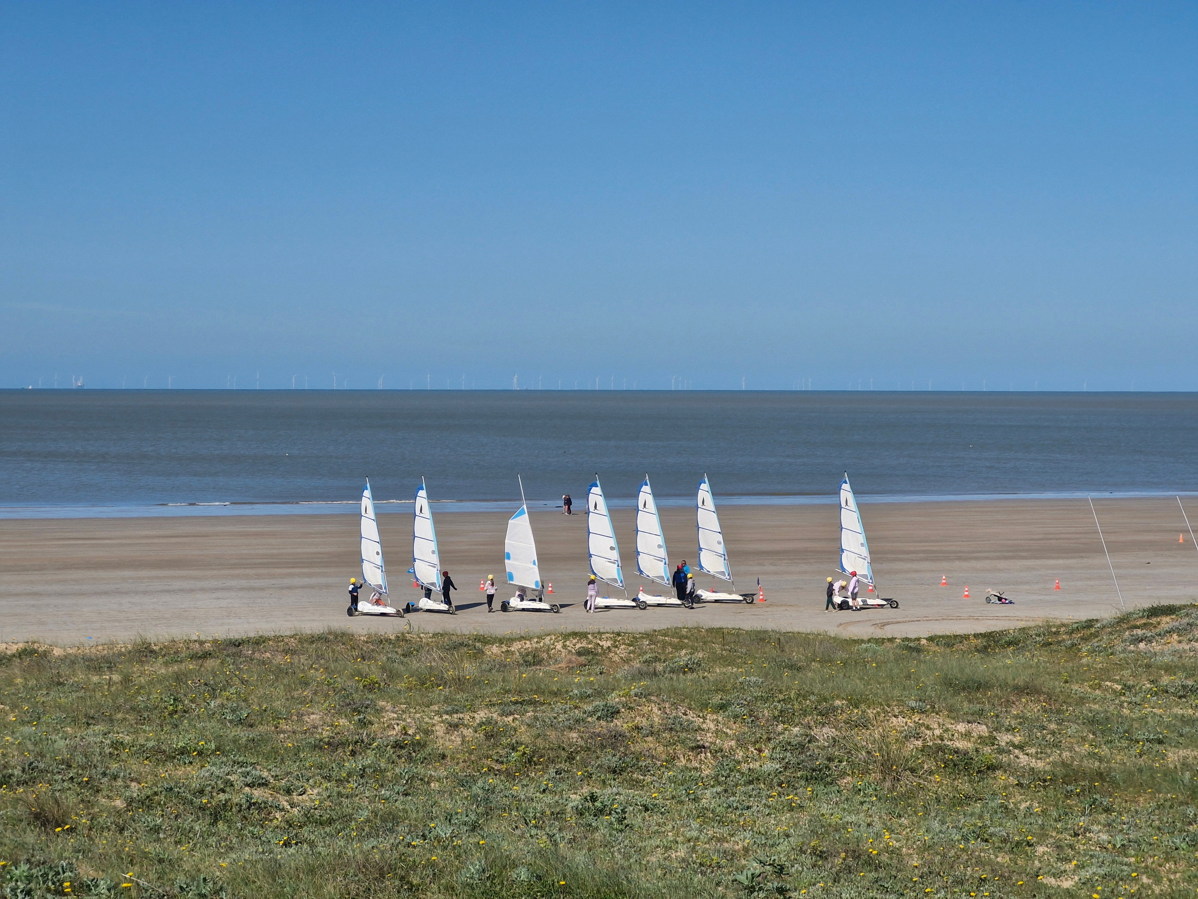 Une flotte de chars à voile alignée sur le sable à marée basse